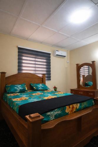 una camera da letto con un letto di legno e uno specchio di DAL Multibiz Guest House a Paynesville