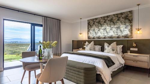 a bedroom with a large bed and a table and chairs at Plettenvale Wines in Plettenberg Bay