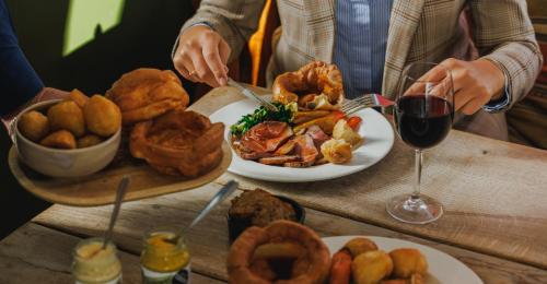 a table with plates of food and a glass of wine at The Fleece in Witney