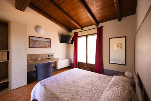 a bedroom with a bed and a desk and a window at Agriturismo Greppi in Crescentino