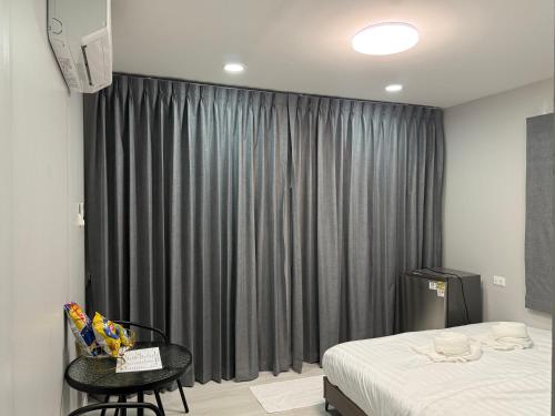a bedroom with a bed and a black curtain at บ้านสวนจุกทิพย์ โฮมสเตย์ in Ban Sam Kaeo
