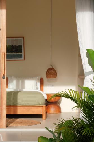 a bedroom with a bed and a potted plant at Summer Promo - 2 BR villa, big pool & garden in Kuta Lombok