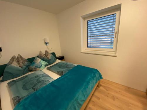 a bedroom with a bed with blue sheets and a window at Haus Caré in Weissensee