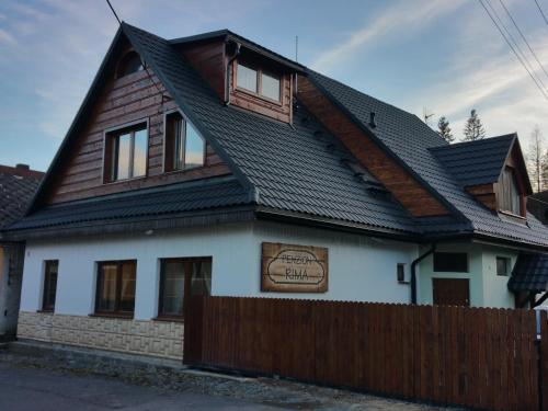 une maison avec un toit noir et une clôture en bois dans l'établissement Penzion Rima, à Zuberec