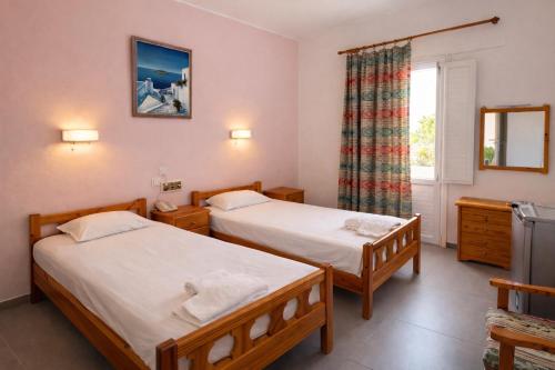 two beds in a room with a window at Babis Hotel in Karterados