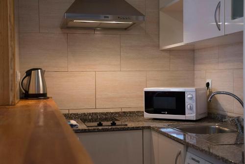 a kitchen with a microwave and a sink at Apartamentos Ripoll Ibiza in Ibiza Town
