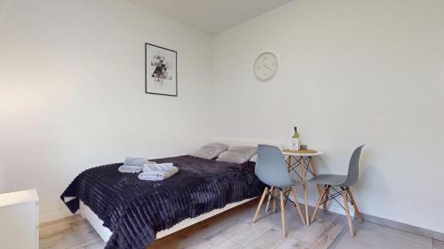 a bedroom with a bed and a table and a clock at Studio Fibra Metrio in Rybnik