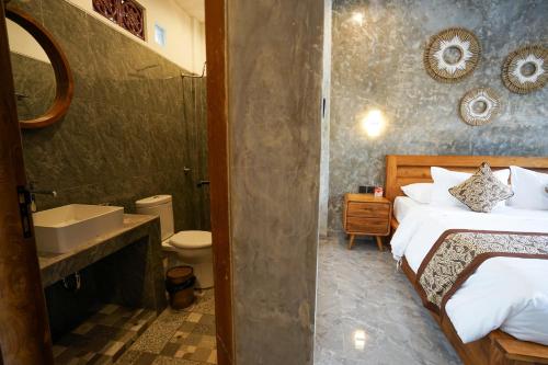 a bedroom with a bed and a bathroom with a sink at Sandat Garden House in Ubud