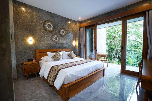a bedroom with a large bed and a large window at Sandat Garden House in Ubud