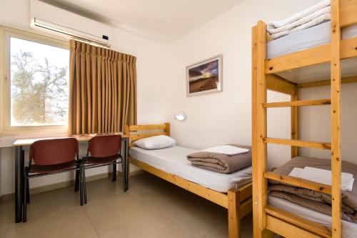 a room with bunk beds and a table and a desk at SPNI Har Hanegev Field School in Mitzpe Ramon