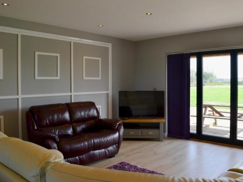 a living room with a leather chair and a television at Aimmee's Lodge - Ukc2203 in Doddington