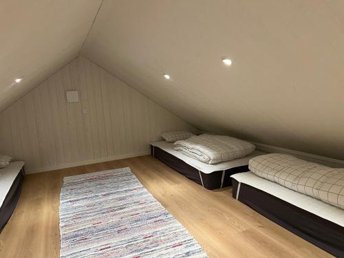 a attic room with two beds and a rug at Hjortgården in Mora