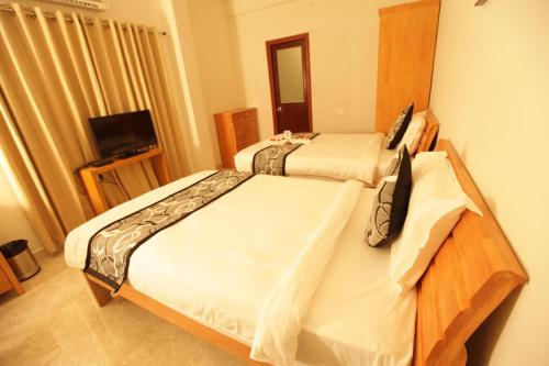 a bedroom with two beds and a television in it at Grand Cascade Chennai in Chennai