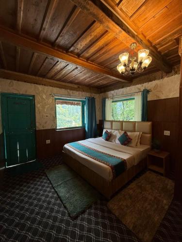 a bedroom with a large bed and a chandelier at havana stays in Jibhi