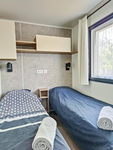 a bedroom with a bed and a window at Mobil home - La carabasse 4 Etoiles - 3 chambres in Vias