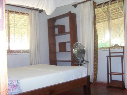 a bedroom with a bed and a mirror and windows at Villa Miadana in Mahajanga