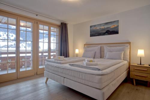 a bedroom with a large white bed with a balcony at Chalet La Gioventu - GRIWA RENT AG in Grindelwald