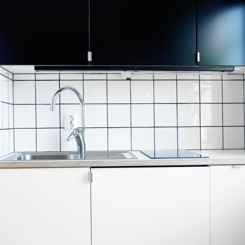 a kitchen sink with a faucet and white tiles at Våningen vid Havet in Simrishamn