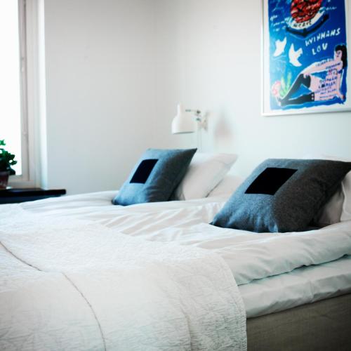 a large white bed with blue pillows on it at Våningen vid Havet in Simrishamn