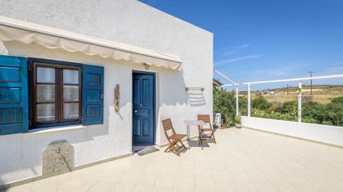a patio with a table and chairs and a blue door at Firiki Studios in Zefiría
