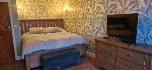 a bedroom with a bed and a dresser with a mirror at Luxury, Modern Barn Conversion in Thursford