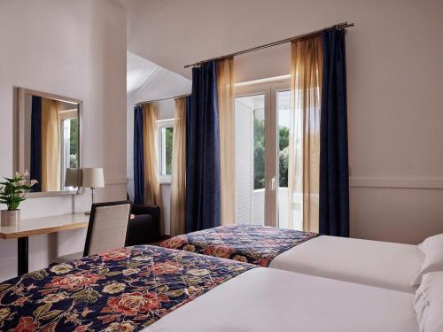 a hotel room with two beds and a desk and windows at Amadria Park Apartments Šibenik in Šibenik