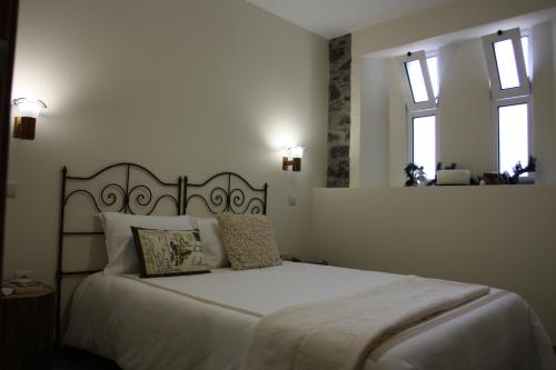 a bedroom with a large white bed with two windows at A Casa Estrelícia-Dourada Garcês in São Vicente