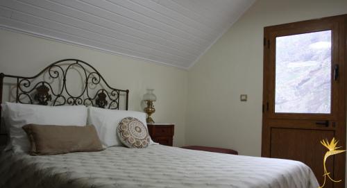 a bedroom with a bed and a window and a door at A Casa Estrelícia-Dourada Garcês in São Vicente