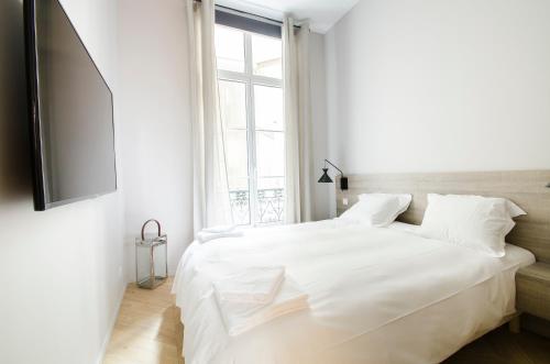 a white bedroom with a large bed and a window at Dreamyflat - Apartment Opera 2 in Paris