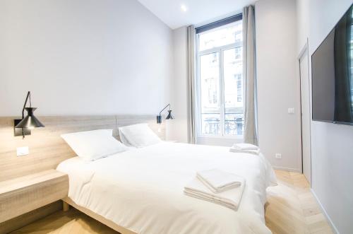 a white bedroom with a large bed and a tv at Dreamyflat - Apartment Opera 1 in Paris