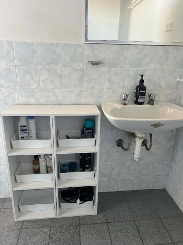 a bathroom with a sink and a white cabinet with shelves at Beach House Studio in Busselton