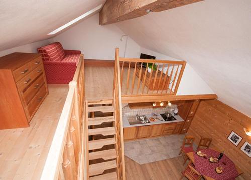 an attic room with a staircase and a red couch at Lechnerhof in Braies