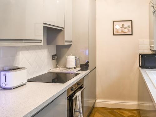 a kitchen with white cabinets and a counter top at Nala's Cottage in Skegness