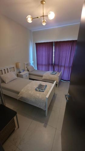 a bedroom with two beds and a purple curtain at Elegant and comfortably furnished 2BRH apartment in a quiet area! in Dubai
