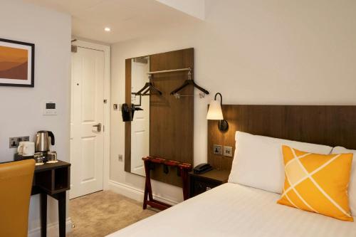 a bedroom with a bed and a desk and a mirror at Four Points Flex by Sheraton London Kensington Olympia in London