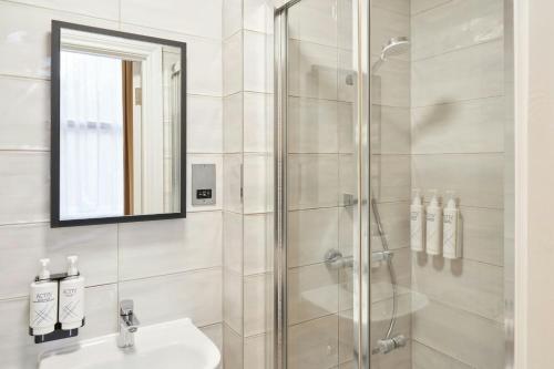 a bathroom with a shower and a sink and a mirror at Four Points Flex by Sheraton London Kensington Olympia in London