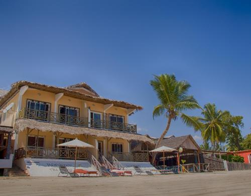 un edificio en la playa con sillas y sombrillas en Hotel-Residence Au Sable Blanc, en Madirokely