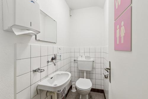 a white bathroom with a toilet and a sink at Sigma Self Check-in Hostel in Zurich