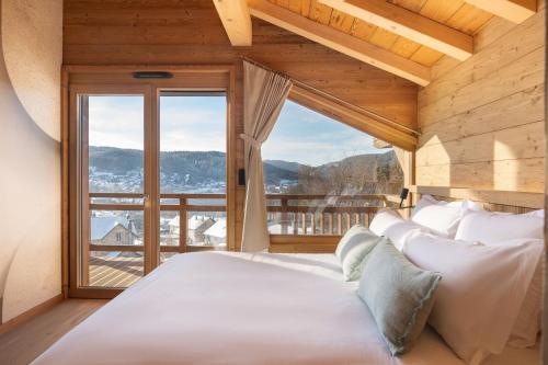 a bedroom with a large bed with a large window at Sorelle Chalet, spa, indoor pool, lake view in Gérardmer