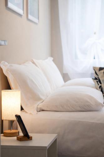 a bed with white pillows and a table with a lamp at Casa Rosetta - Relax in Centro - Parcheggio Privato, Mare a 2 Passi in Bordighera