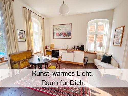ein Wohnzimmer mit Sofa und Tisch in der Unterkunft FeWo "Ebbe" im historischen Denkmal, ruhig & modern mit Stil, Kunst und großem Garten, hochwertiger Ausstattung & zentraler Lage in Esens- 3km zur Nordsee, alles fußläufig erreichbar - ideal für Paare oder kleine Familien in Esens