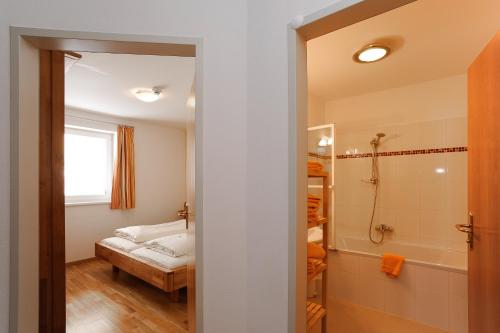 a bathroom with a shower and a bed at Hotel Laaxerhof in Obertauern