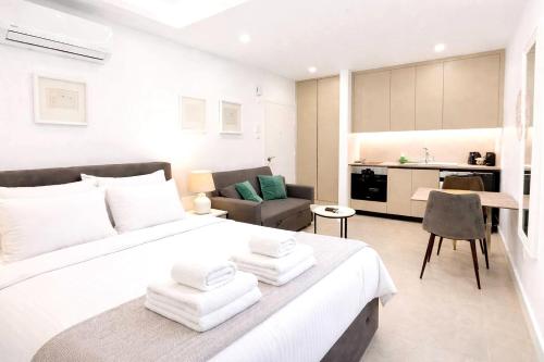 a bedroom with a large white bed and a kitchen at White Arches Studio Suite by TrulyCyprus in Limassol