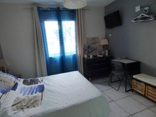 a bedroom with a bed and a desk and a window at Les Amandiers in Abeilhan