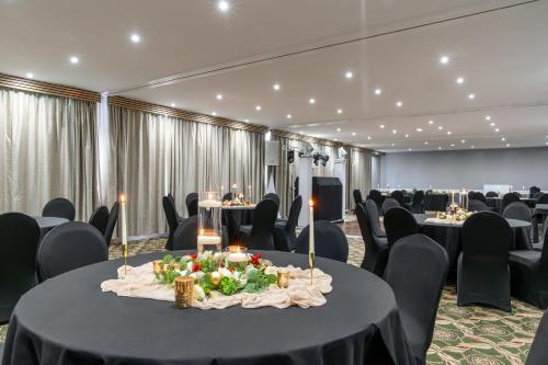 a banquet hall with tables and chairs with a table centerpiece at Airport Hotel Manchester in Manchester
