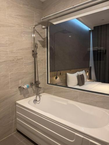 a bathroom with a tub and a large mirror at LION 5 HOTEL in Can Tho