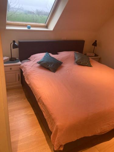a bed with two pillows in a bedroom with a window at De Notelaar in Alveringem