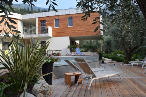 a house with a wooden deck with chairs and a woman on the balcony at "CASABANA" - relax tutto l'anno - giardino - piscina Top in Malcesine