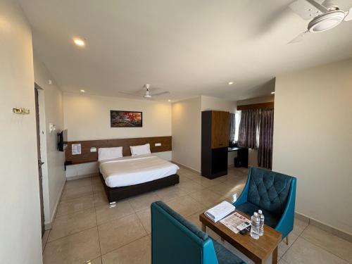 a hotel room with a bed and a table and chairs at Hotel Park Varaahi in Tirupati