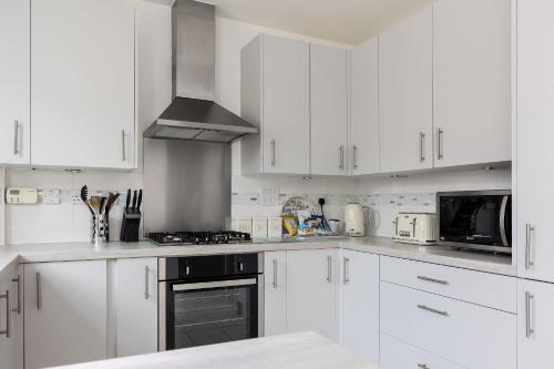 a white kitchen with white cabinets and appliances at Avalon - Walking Distance to Poole Quay and Town in Poole
